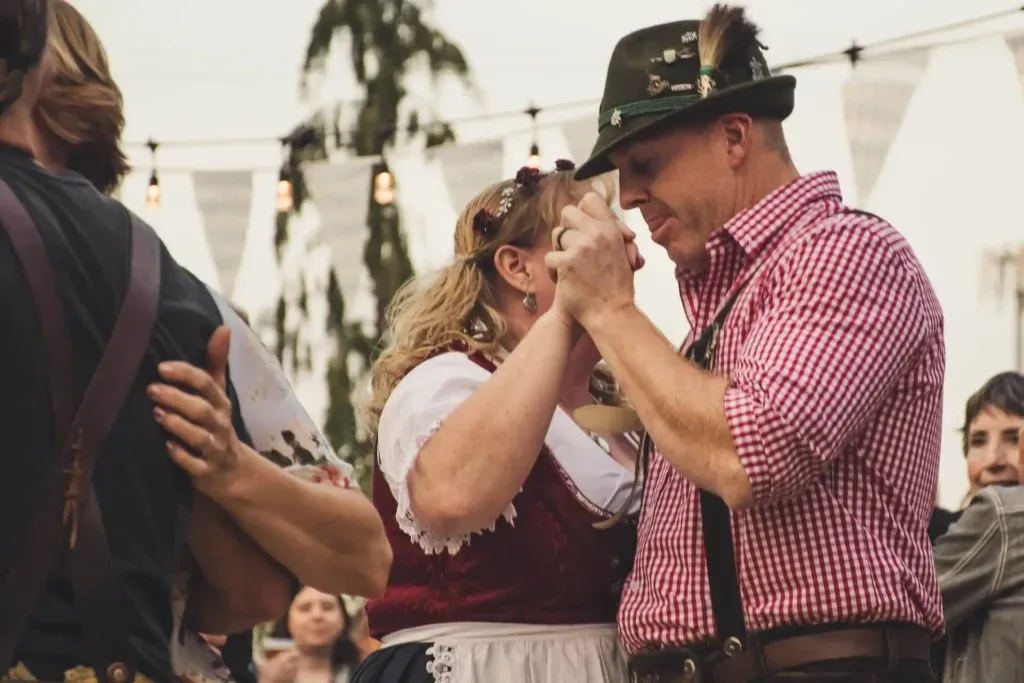 Couple in traditional Bavarian attire dancing at Oktoberfest. - Lederhosen For Sale